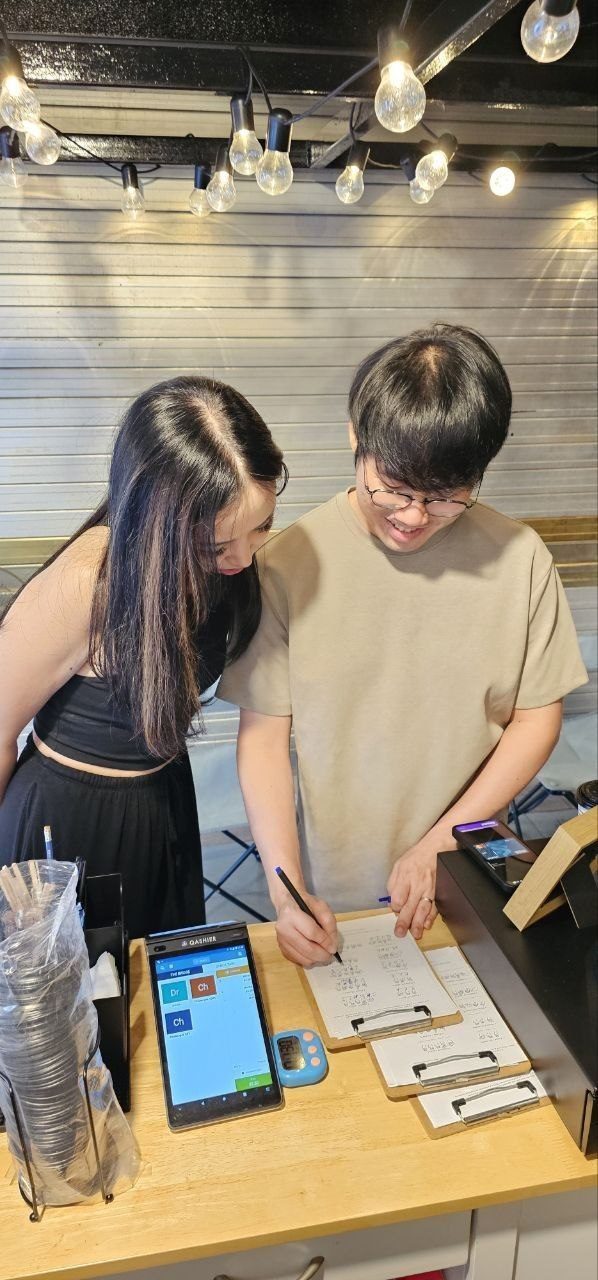 Two customers working through the Braille Challenge worksheets at the kiosk counter
