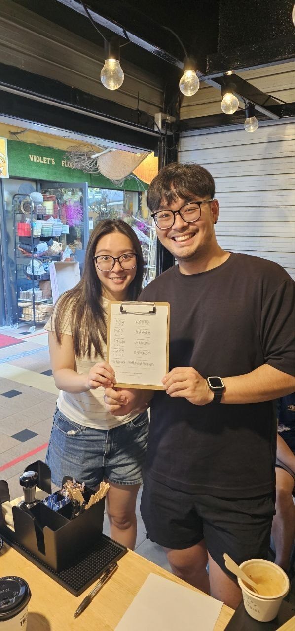 Two smiling customers holding up their completed challenge clipboard